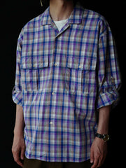 詳細画像: キューバンカラーと胸前のフラップポケットのディテール。チェック柄の鮮明さとシャツの質感を強調。
モデル画像: モデルがMADRAS (マドラス) チェック柄シャツを着用したスタイリング例。実際の着用感やフィット感を視覚的に伝える。