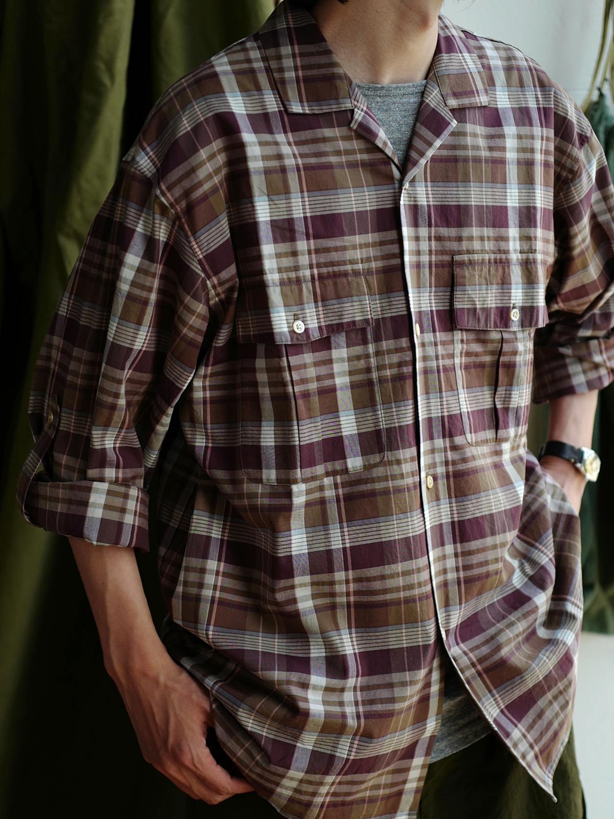 詳細画像: キューバンカラーと胸前のフラップポケットのディテール。チェック柄の鮮明さとシャツの質感を強調。
モデル画像: モデルがMADRAS (マドラス) チェック柄シャツを着用したスタイリング例。実際の着用感やフィット感を視覚的に伝える。