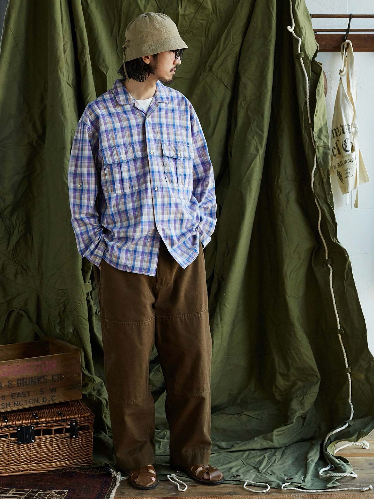 詳細画像: キューバンカラーと胸前のフラップポケットのディテール。チェック柄の鮮明さとシャツの質感を強調。
モデル画像: モデルがMADRAS (マドラス) チェック柄シャツを着用したスタイリング例。実際の着用感やフィット感を視覚的に伝える。