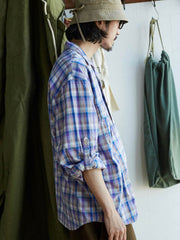 詳細画像: キューバンカラーと胸前のフラップポケットのディテール。チェック柄の鮮明さとシャツの質感を強調。
モデル画像: モデルがMADRAS (マドラス) チェック柄シャツを着用したスタイリング例。実際の着用感やフィット感を視覚的に伝える。