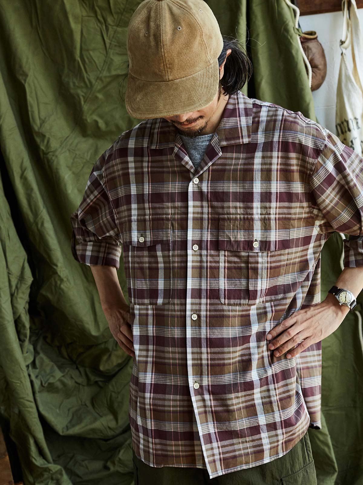 詳細画像: キューバンカラーと胸前のフラップポケットのディテール。チェック柄の鮮明さとシャツの質感を強調。
モデル画像: モデルがMADRAS (マドラス) チェック柄シャツを着用したスタイリング例。実際の着用感やフィット感を視覚的に伝える。