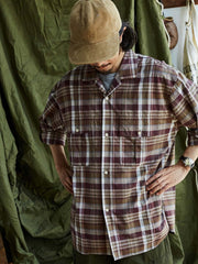 詳細画像: キューバンカラーと胸前のフラップポケットのディテール。チェック柄の鮮明さとシャツの質感を強調。
モデル画像: モデルがMADRAS (マドラス) チェック柄シャツを着用したスタイリング例。実際の着用感やフィット感を視覚的に伝える。