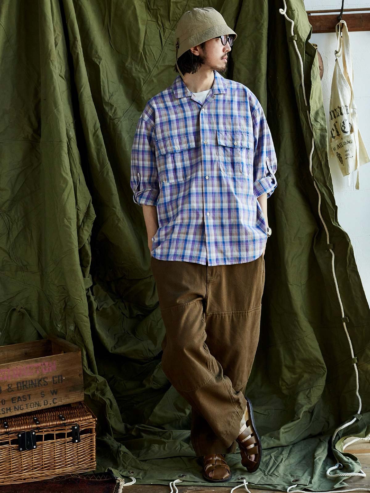 詳細画像: キューバンカラーと胸前のフラップポケットのディテール。チェック柄の鮮明さとシャツの質感を強調。
モデル画像: モデルがMADRAS (マドラス) チェック柄シャツを着用したスタイリング例。実際の着用感やフィット感を視覚的に伝える。