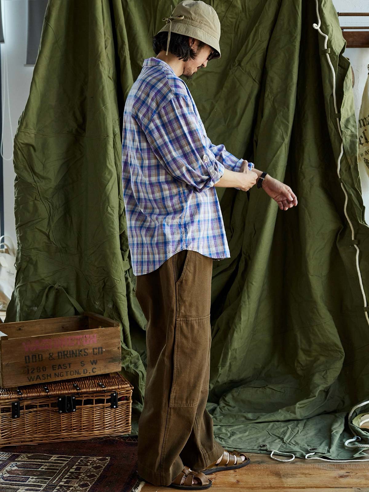 詳細画像: キューバンカラーと胸前のフラップポケットのディテール。チェック柄の鮮明さとシャツの質感を強調。
モデル画像: モデルがMADRAS (マドラス) チェック柄シャツを着用したスタイリング例。実際の着用感やフィット感を視覚的に伝える。