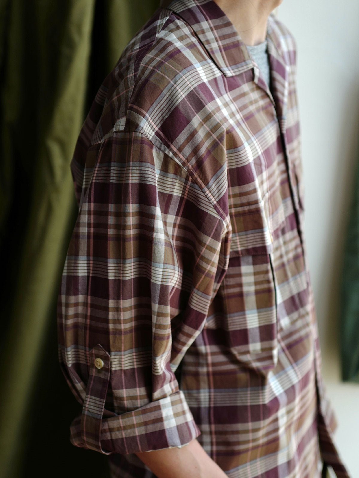 詳細画像: キューバンカラーと胸前のフラップポケットのディテール。チェック柄の鮮明さとシャツの質感を強調。
モデル画像: モデルがMADRAS (マドラス) チェック柄シャツを着用したスタイリング例。実際の着用感やフィット感を視覚的に伝える。