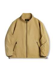 凹凸感のあるチェック柄とアクセントジッパーが特徴の軽量防風ジャケット。スタンドカラーとゴム袖口で快適な着心地。