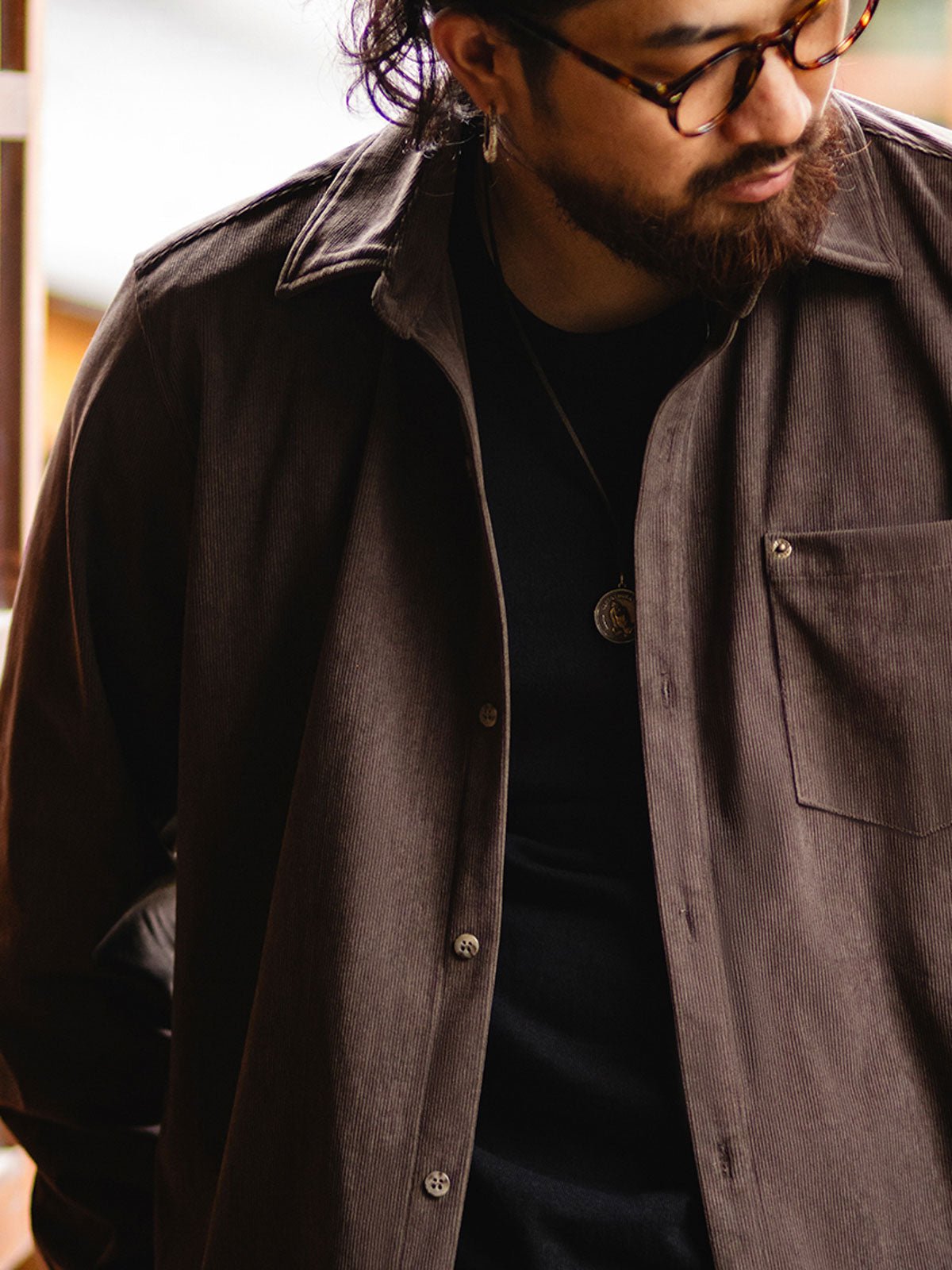 詳細画像:胸元のリベットデザインと裾のNAVAJOラベル。ヴィンテージ感のあるディテール。
モデル画像:モデルが着用したコーデュロイシャツの全身コーディネート。秋冬向けのカジュアルなルーズフィットスタイル。