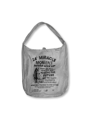 グレーのパッカブルナイロンショルダーバッグ、フロントにメッセージプリント、内蔵ポケットで折りたたみ可能