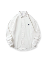 胸元にワッペン刺繍があしらわれたウォッシュ加工コットン長袖シャツの全体像。