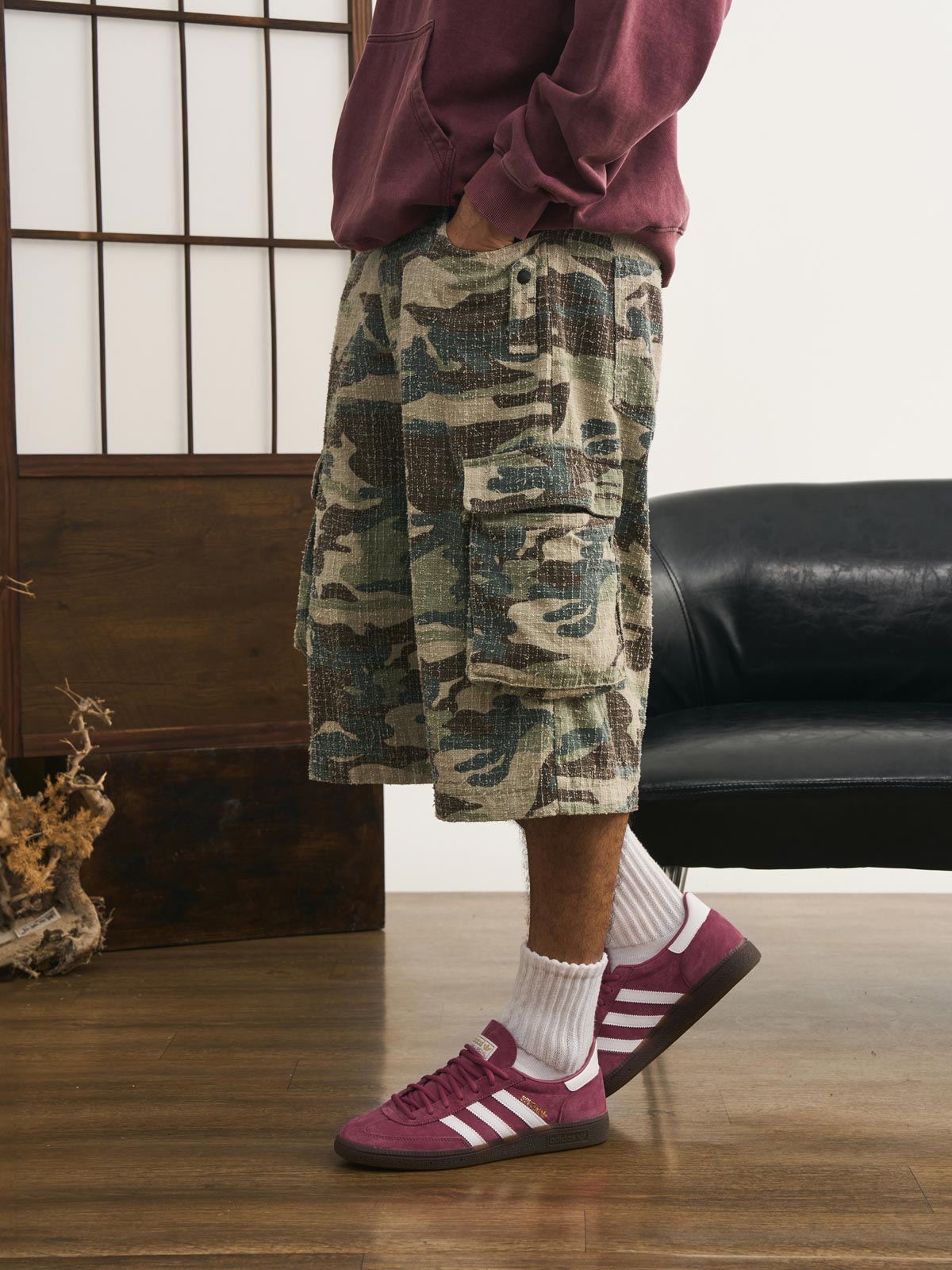 モデルが迷彩七分丈パンツを着用し、カジュアルなトップスと組み合わせた個性的なヴィンテージスタイルを演出。