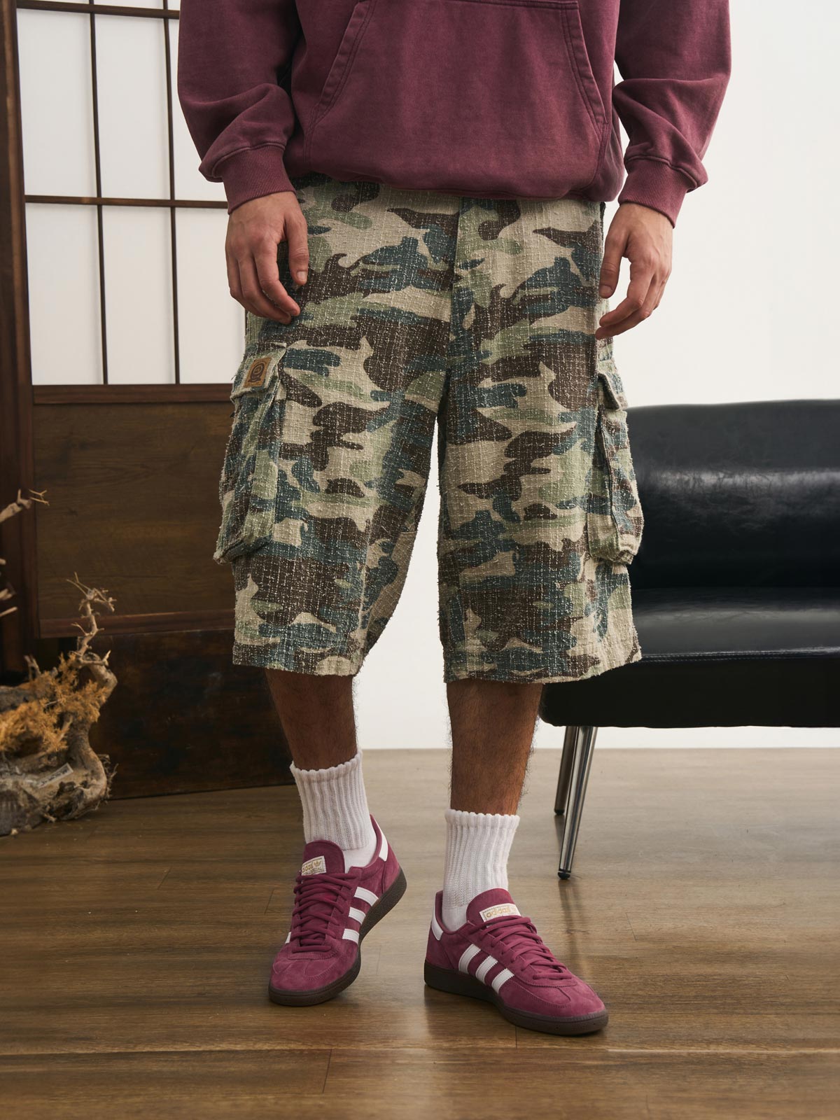 モデルが迷彩七分丈パンツを着用し、カジュアルなトップスと組み合わせた個性的なヴィンテージスタイルを演出。