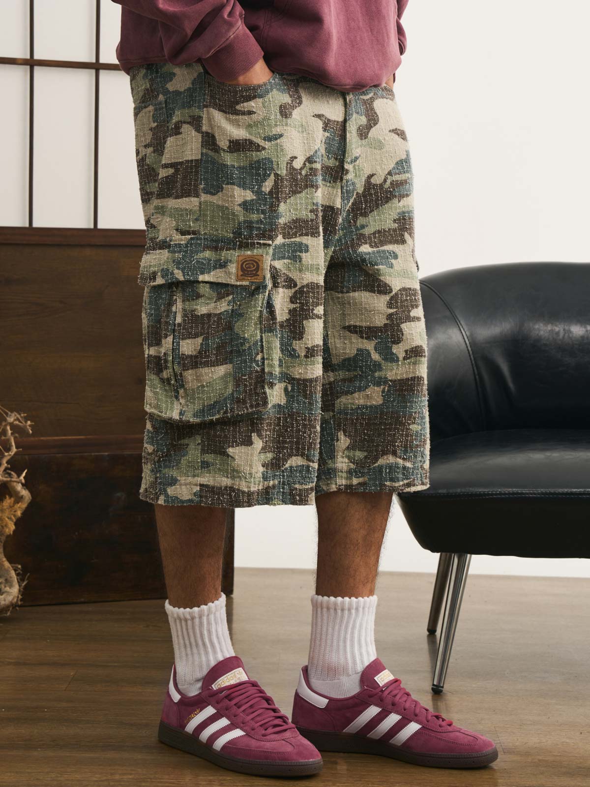 モデルが迷彩七分丈パンツを着用し、カジュアルなトップスと組み合わせた個性的なヴィンテージスタイルを演出。