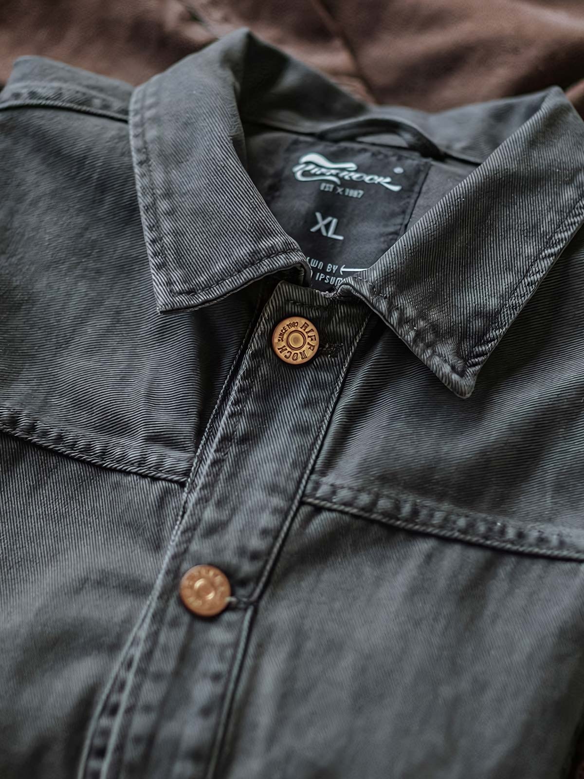 製品画像:アメカジヴィンテージウォッシュ加工ワークジャケットの正面展示。ヴィンテージ感とワークウェアの機能性が融合した一着。
詳細画像:ヴィンテージメタルボタンとダブルステッチのディテール。耐久性とデザイン性を兼ね備えたディテール。