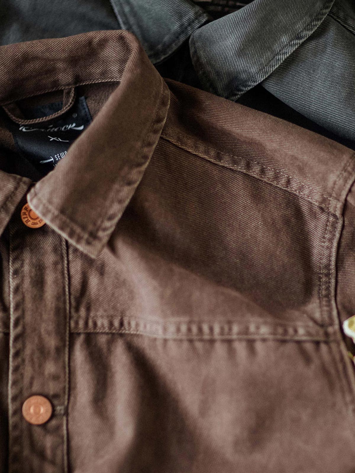 製品画像:アメカジヴィンテージウォッシュ加工ワークジャケットの正面展示。ヴィンテージ感とワークウェアの機能性が融合した一着。
詳細画像:ヴィンテージメタルボタンとダブルステッチのディテール。耐久性とデザイン性を兼ね備えたディテール。