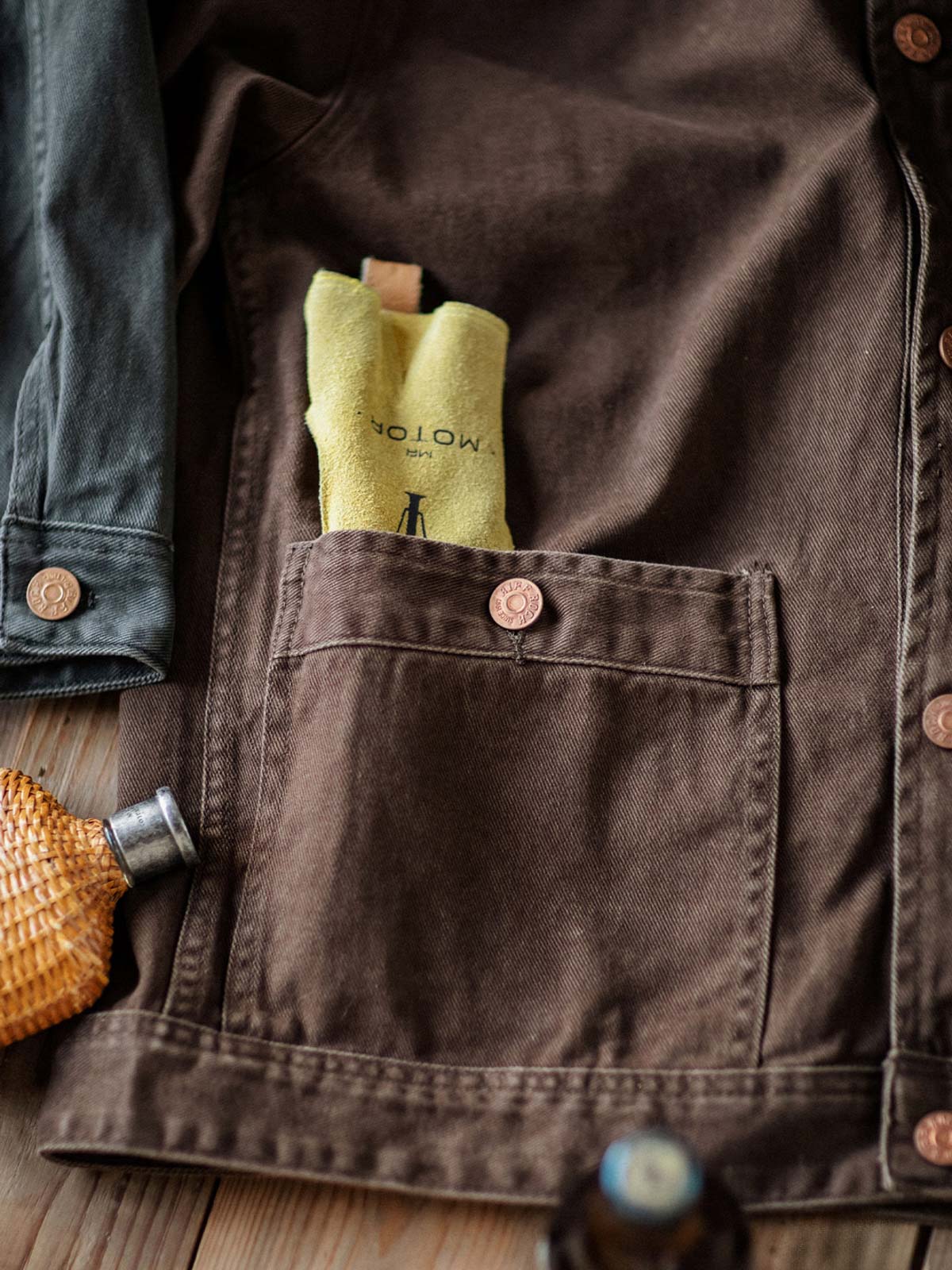 製品画像:アメカジヴィンテージウォッシュ加工ワークジャケットの正面展示。ヴィンテージ感とワークウェアの機能性が融合した一着。
詳細画像:ヴィンテージメタルボタンとダブルステッチのディテール。耐久性とデザイン性を兼ね備えたディテール。