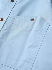 製品画像: クラシックなスタンドカラーと肘パッチが特徴のワークシャツ。シンプルでありながらスタイリッシュなデザインが際立っています。
詳細画像: 非対称ポケットと肘パッチが施されたディテール。デザインと機能性が融合した袖部分が強調されています。