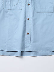 製品画像: クラシックなスタンドカラーと肘パッチが特徴のワークシャツ。シンプルでありながらスタイリッシュなデザインが際立っています。
詳細画像: 非対称ポケットと肘パッチが施されたディテール。デザインと機能性が融合した袖部分が強調されています。