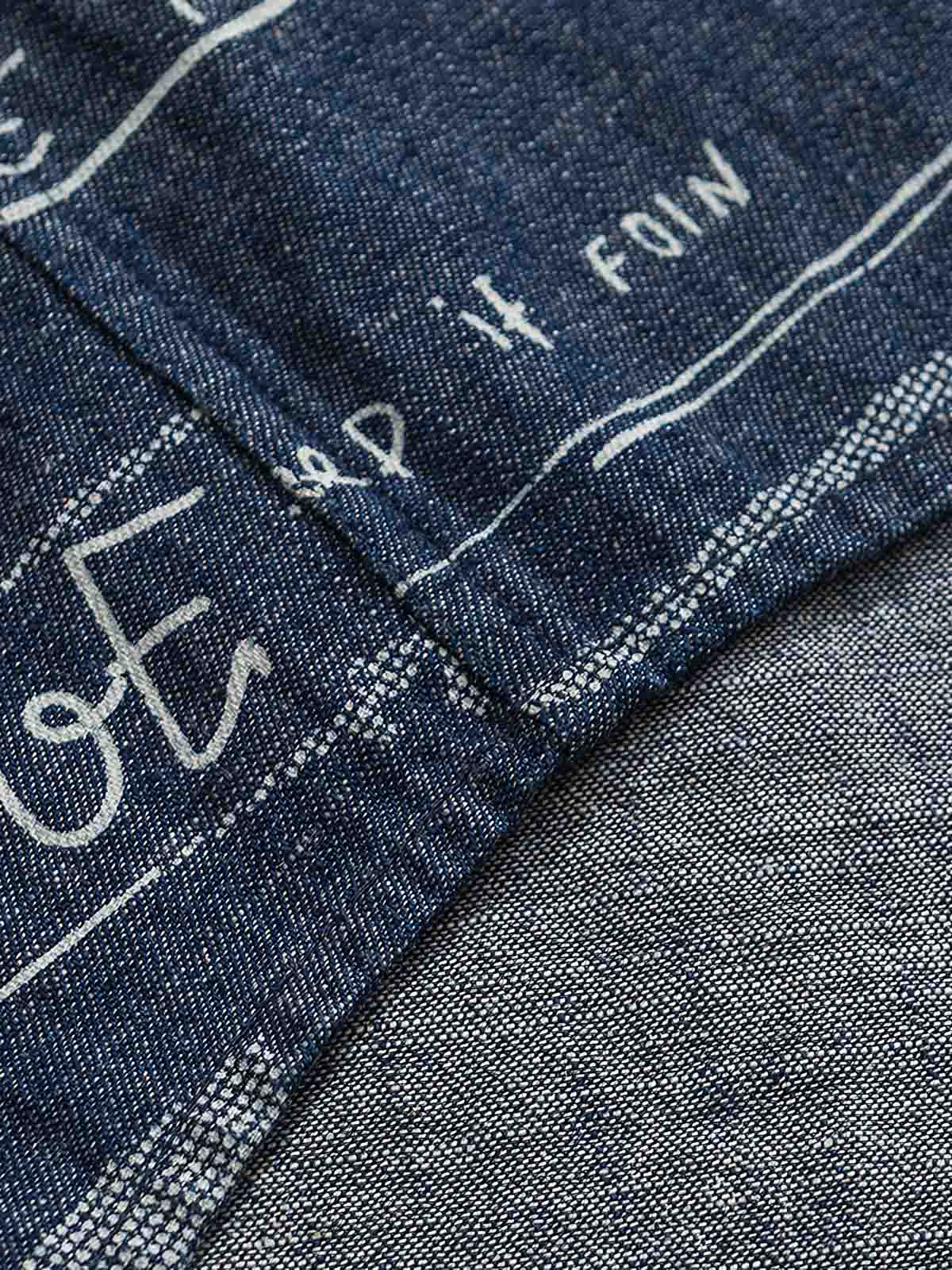 デニム半袖シャツの文字プリントディテール。厳選されたデニム素材と高品質なウォッシュ加工が施され、洗練された外見と耐久性を実現しています。