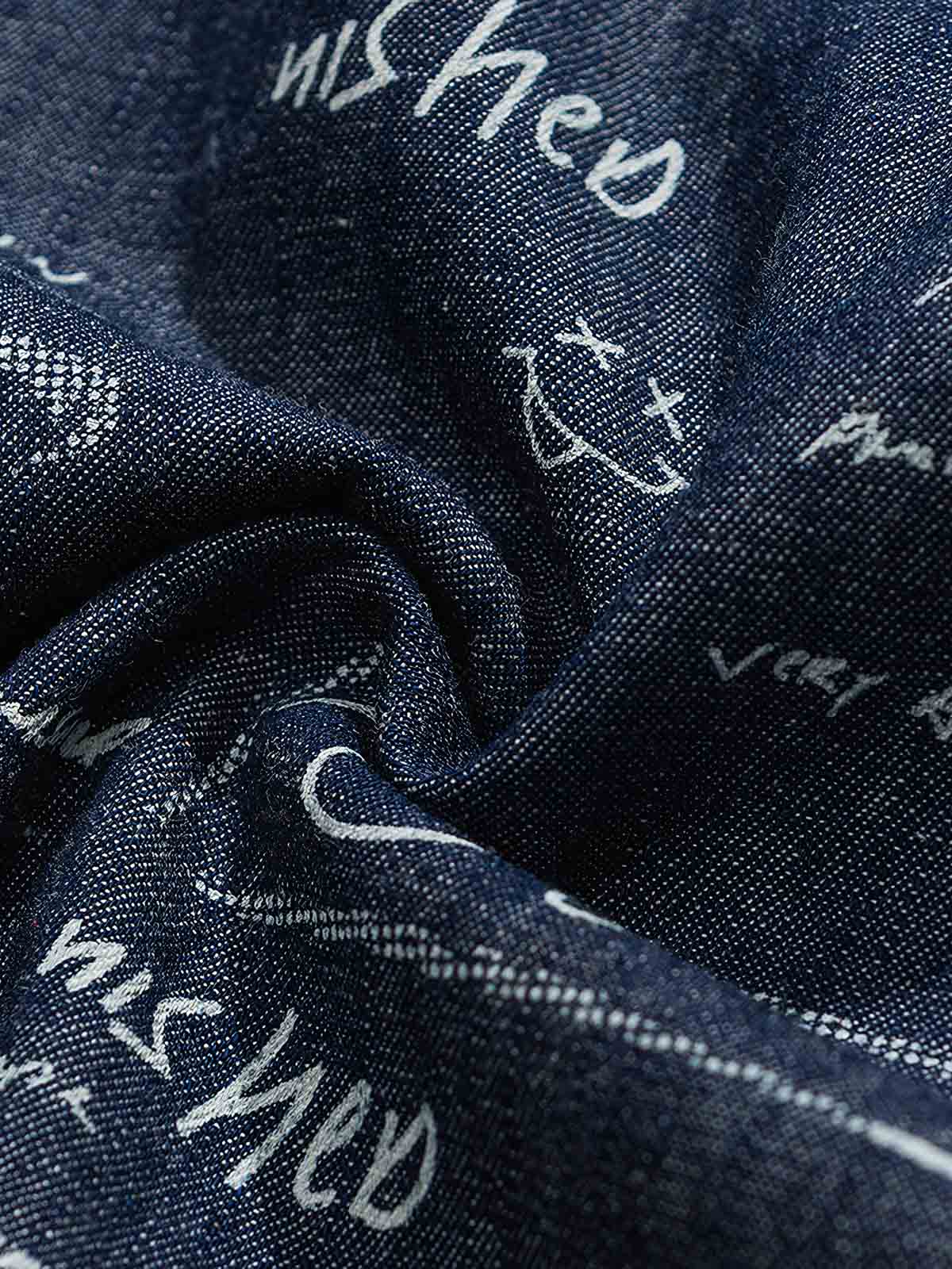 デニム半袖シャツの文字プリントディテール。厳選されたデニム素材と高品質なウォッシュ加工が施され、洗練された外見と耐久性を実現しています。