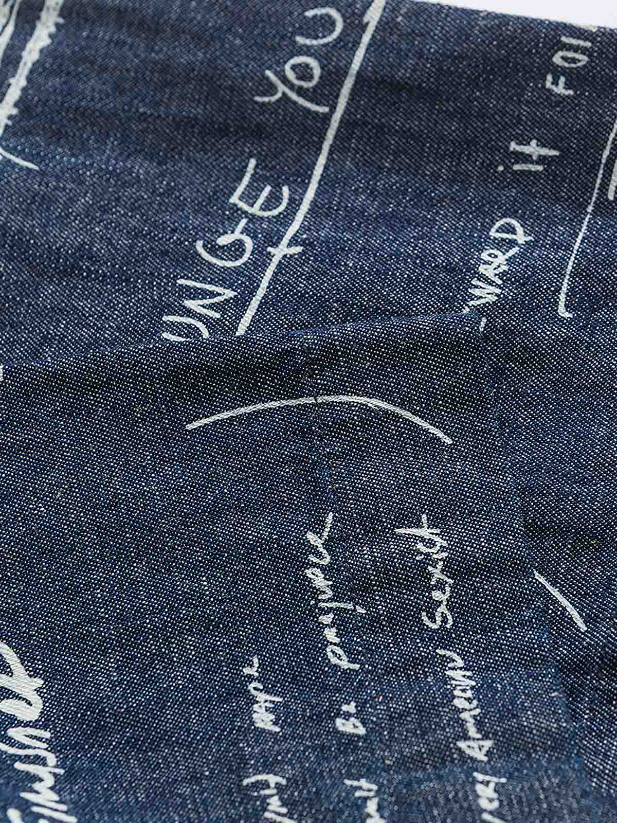 デニム半袖シャツの文字プリントディテール。厳選されたデニム素材と高品質なウォッシュ加工が施され、洗練された外見と耐久性を実現しています。