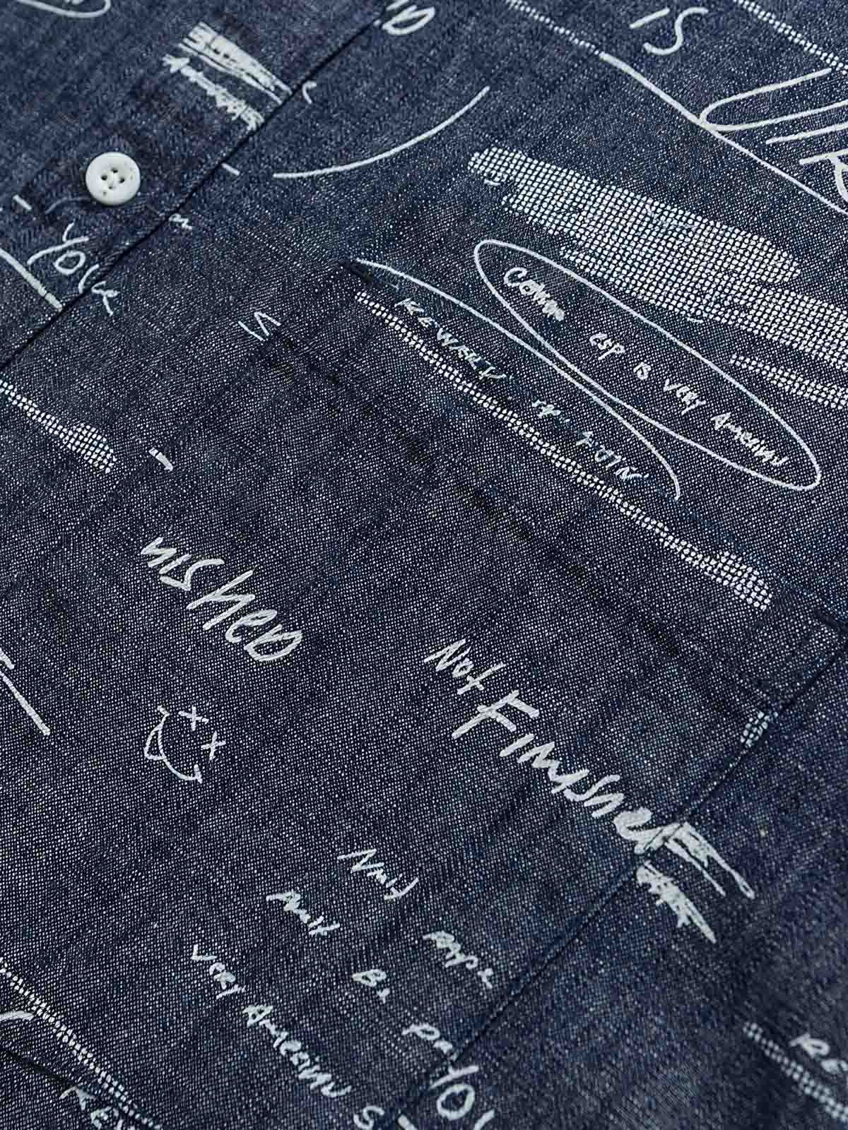 デニム半袖シャツの文字プリントディテール。厳選されたデニム素材と高品質なウォッシュ加工が施され、洗練された外見と耐久性を実現しています。