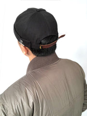 モデルがカーキ色のキャンバスメタルバッジビーニーを着用し、アクティブなストリートスタイルを演出。