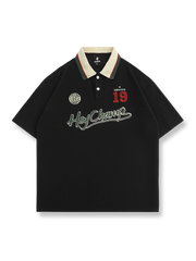 アイビーリーグ風ポロシャツ、胸元の精緻な刺繍と襟のコントラストストライプが特徴。