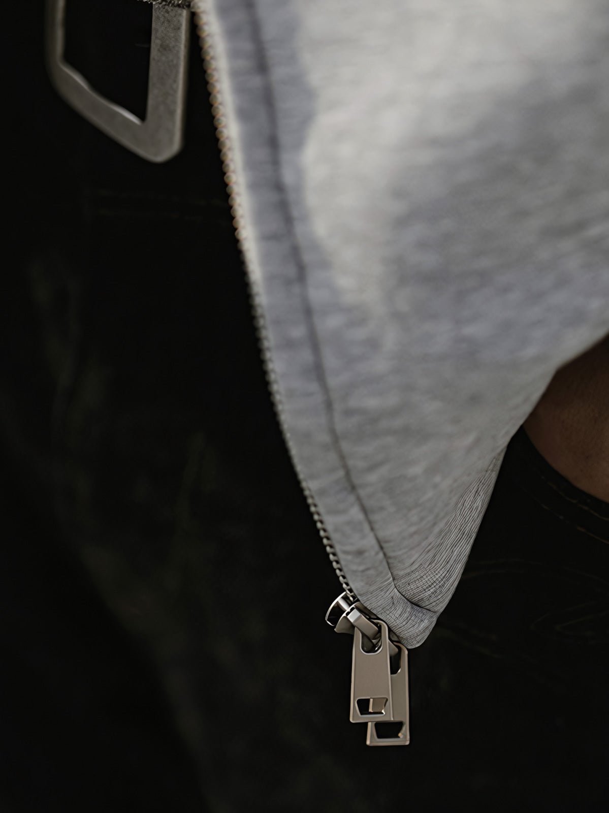 製品画像: グレーのエアレイヤースタイルカットフード付きパーカの正面展示
詳細画像: ダブルジップメタルファスナーと三角カットデザインのディテール展示