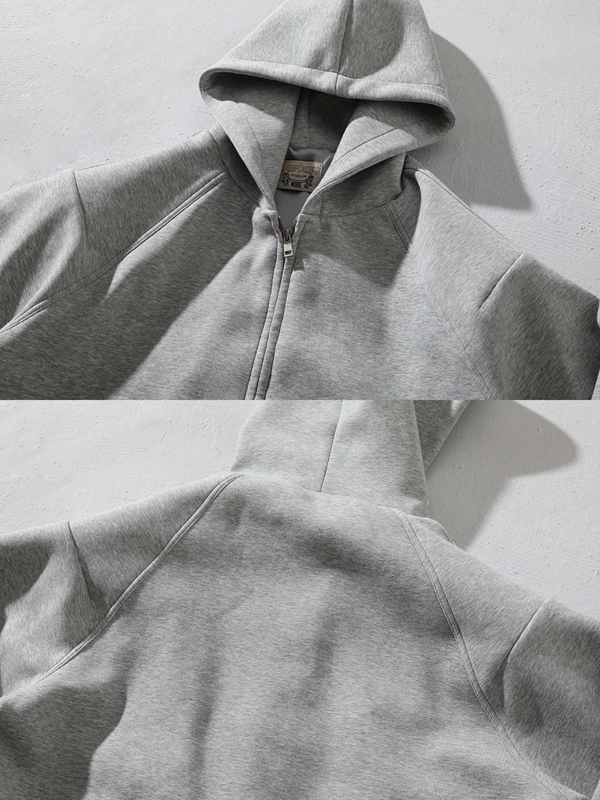 製品画像: グレーのエアレイヤースタイルカットフード付きパーカの正面展示
詳細画像: ダブルジップメタルファスナーと三角カットデザインのディテール展示