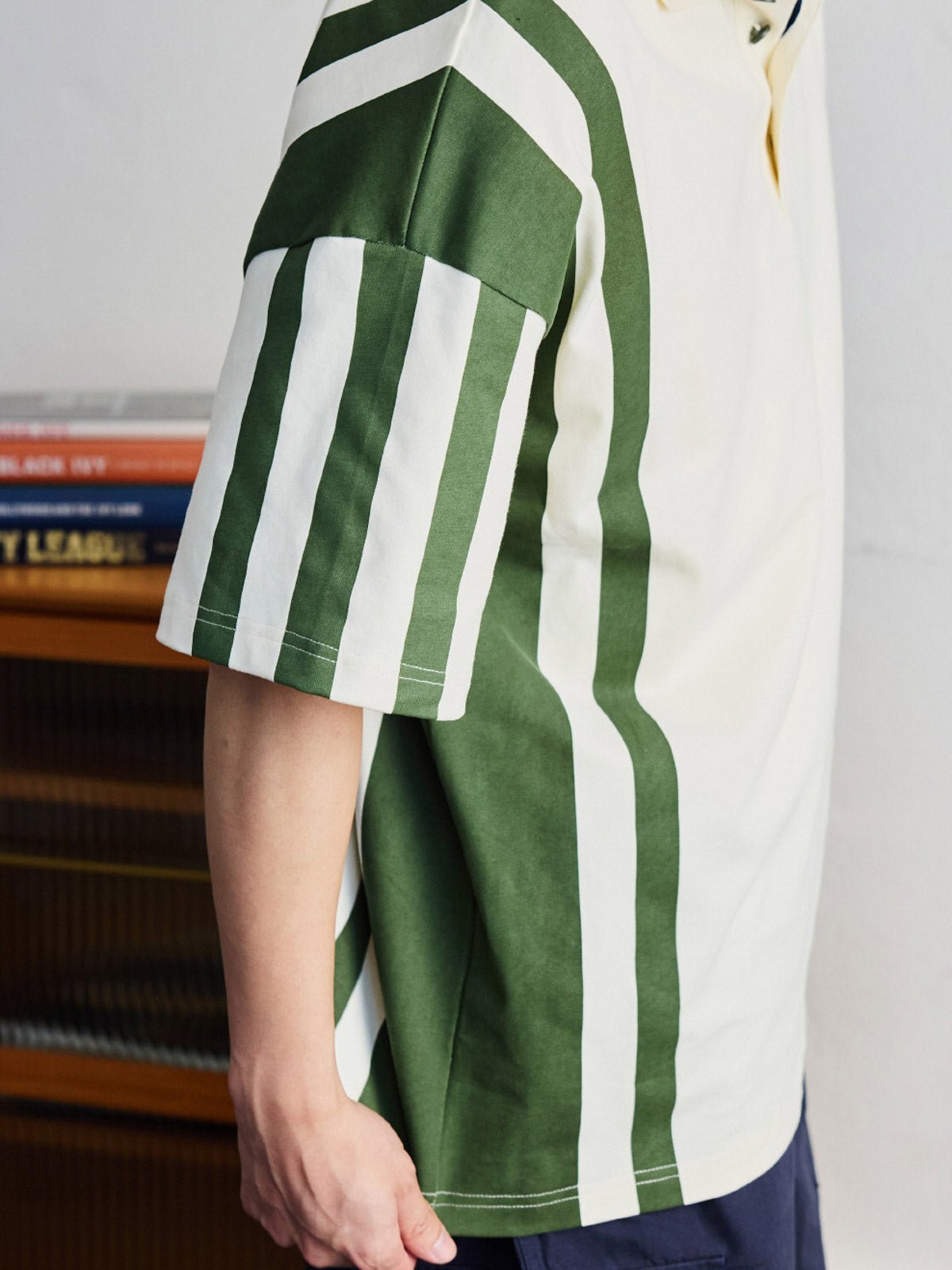 ポロシャツの草緑色ボタンと襟のディテールを特集し、洗練された作りを示す。