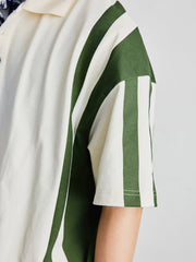 ポロシャツの草緑色ボタンと襟のディテールを特集し、洗練された作りを示す。