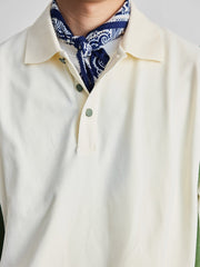 ポロシャツの草緑色ボタンと襟のディテールを特集し、洗練された作りを示す。