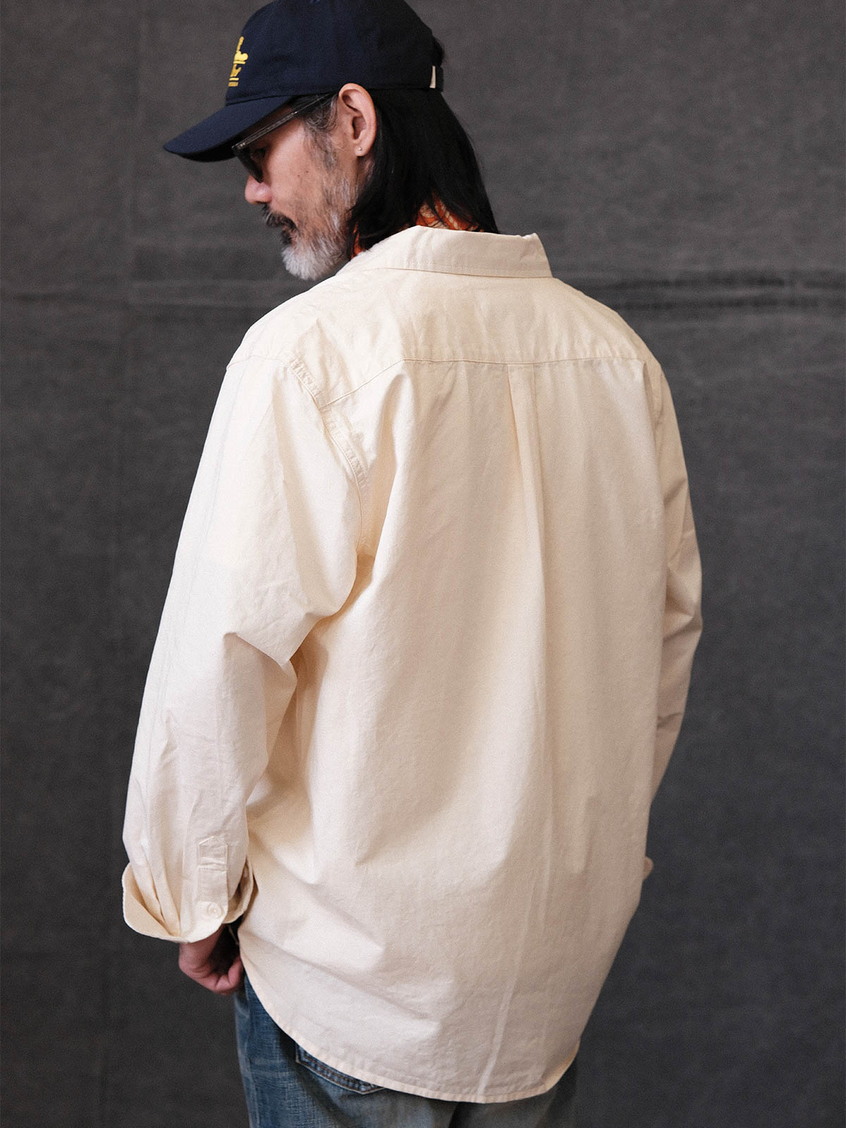 詳細画像: クラシックルーズフィット長袖シャツの高品質な縫製と樹脂ボタンのディテール
モデル画像: ルーズフィットのホワイトシャツを着用したモデルのコーディネート、都会的な通勤スタイル