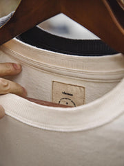 ヘビーウェイトのコットンハスク素材の詳細とダブルレイヤーのアームホールのクローズアップ。素材の厚みと耐摩耗性を強調し、デザインの階層感を示しています。