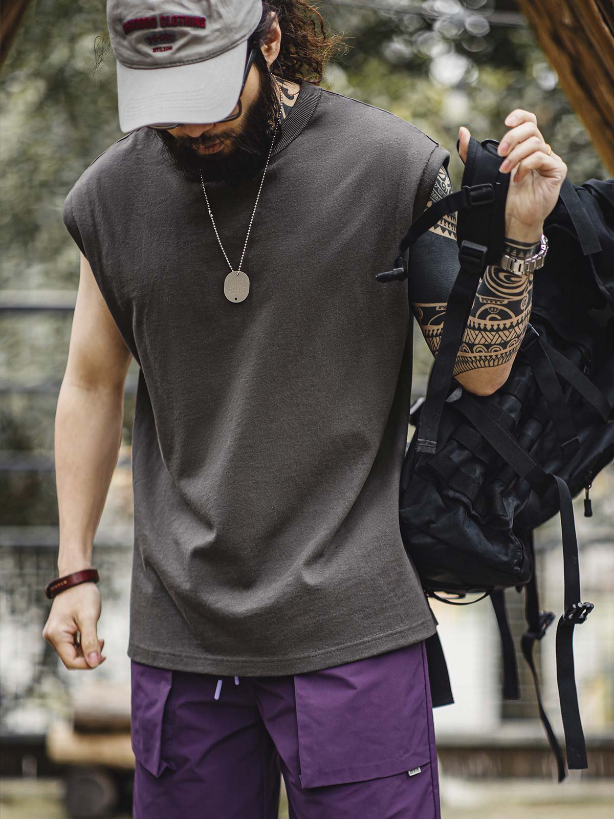 モデルがヘビーウェイトコットンハスクのスリーブレスTシャツを着用し、ルーズフィットのショートパンツとスポーツシューズでスタイリング。リラックスしたカリフォルニアの夏のスタイルを演出しています。