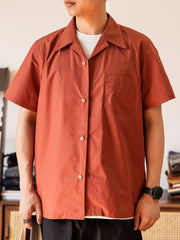 モデルがビビッドなレッドのキューバカラーシャツを着用し、カジュアルパンツとキャンバスシューズでリラックスしたスタイルを演出する画像。