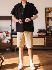 モデルがビビッドなレッドのキューバカラーシャツを着用し、カジュアルパンツとキャンバスシューズでリラックスしたスタイルを演出する画像。