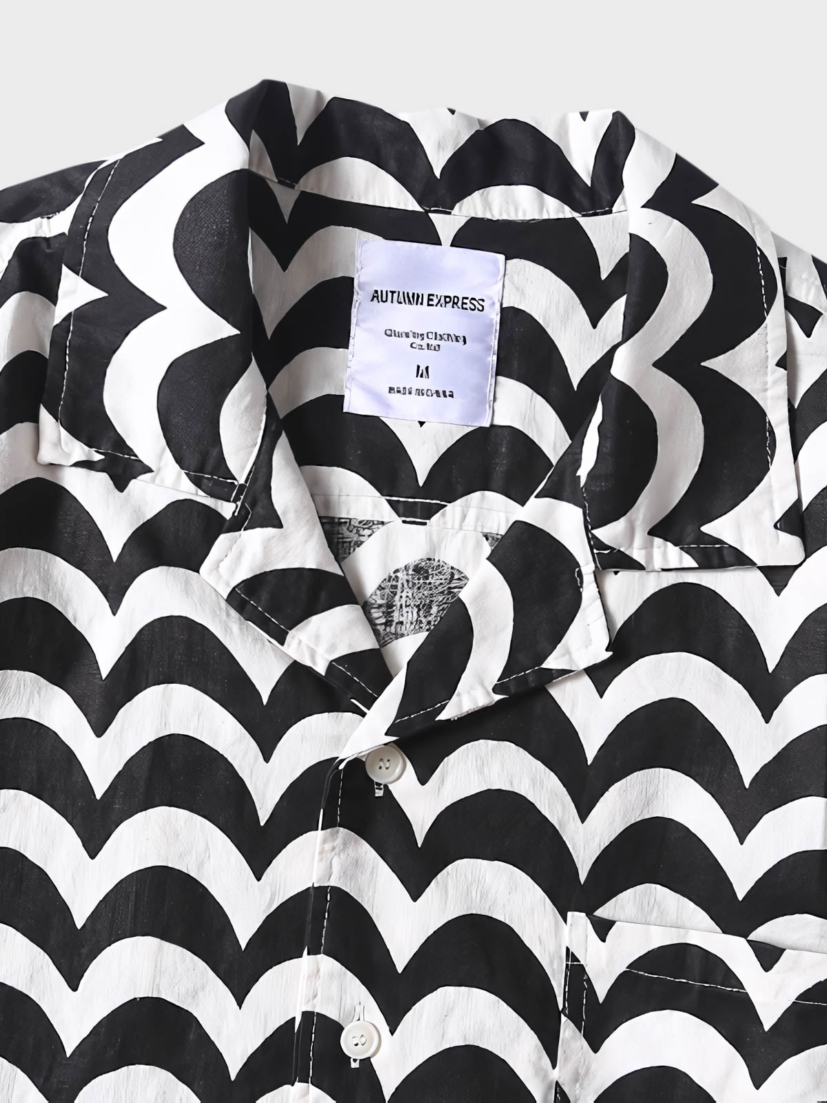 リネンシャツの細かな波状パターンのクローズアップ。黒と白のコントラストが特徴で、精緻な縫製技術を見せる。