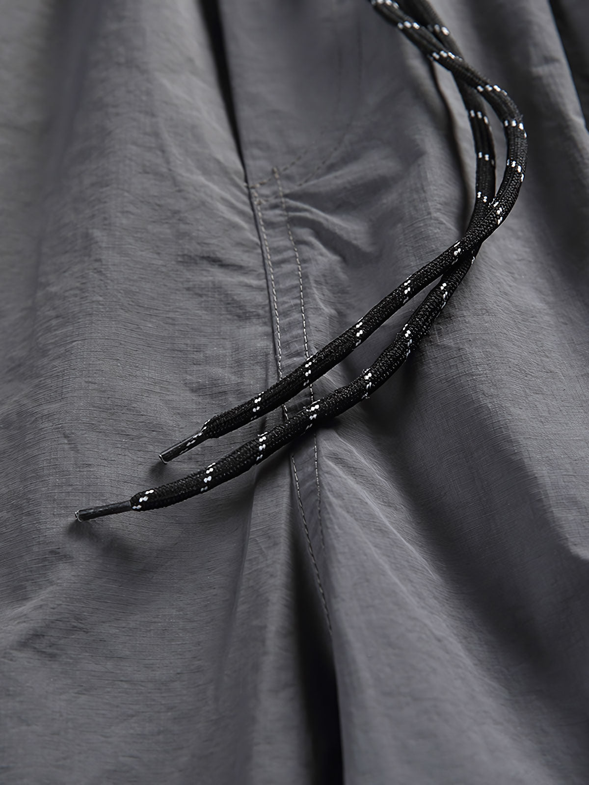 非対称パッチワークナイロンショーツの詳細クローズアップ。耐久性と速乾性に優れた100%ナイロン素材を使用し、独創的なデザインの特徴を強調しています。」