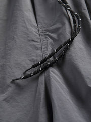 非対称パッチワークナイロンショーツの詳細クローズアップ。耐久性と速乾性に優れた100%ナイロン素材を使用し、独創的なデザインの特徴を強調しています。」