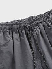 非対称パッチワークナイロンショーツの詳細クローズアップ。耐久性と速乾性に優れた100%ナイロン素材を使用し、独創的なデザインの特徴を強調しています。」