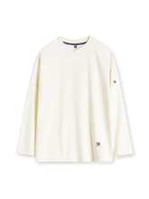 オフホワイトのロングスリーブTシャツ、二の腕のボタン留めタブとリブの襟元、裾のラベル付き