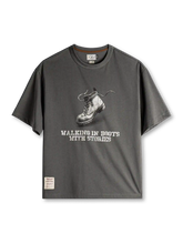 ダークグレーのTシャツ、胸に素描風のワークブーツとステンシル風の英字プリント、裾のラベル付き