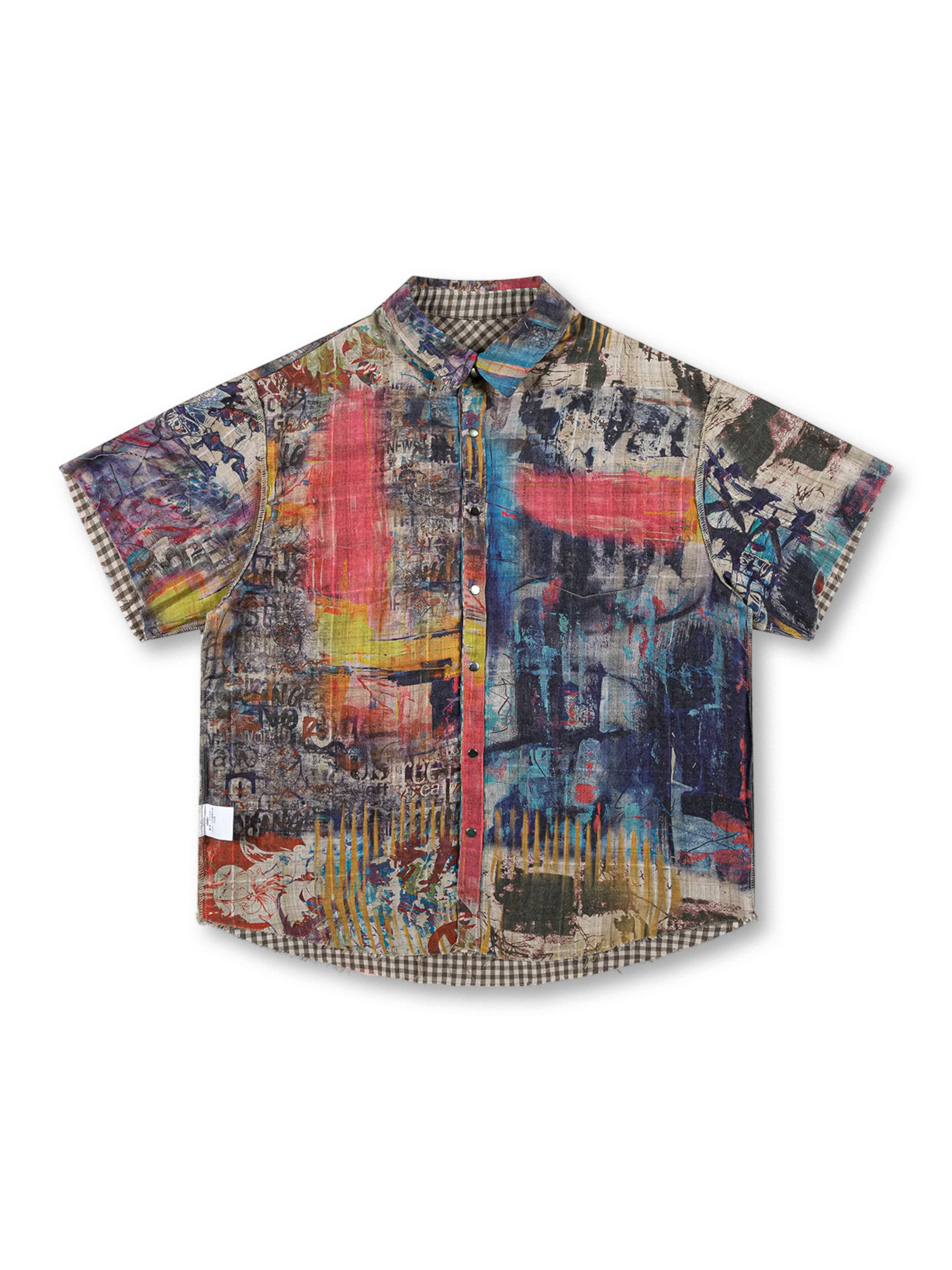 鮮やかなグラフィティプリントとブラウンチェックのリバーシブルデザイン、切りっぱなし裾とダメージ加工が特徴の100%コットンオーバーサイズシャツ。