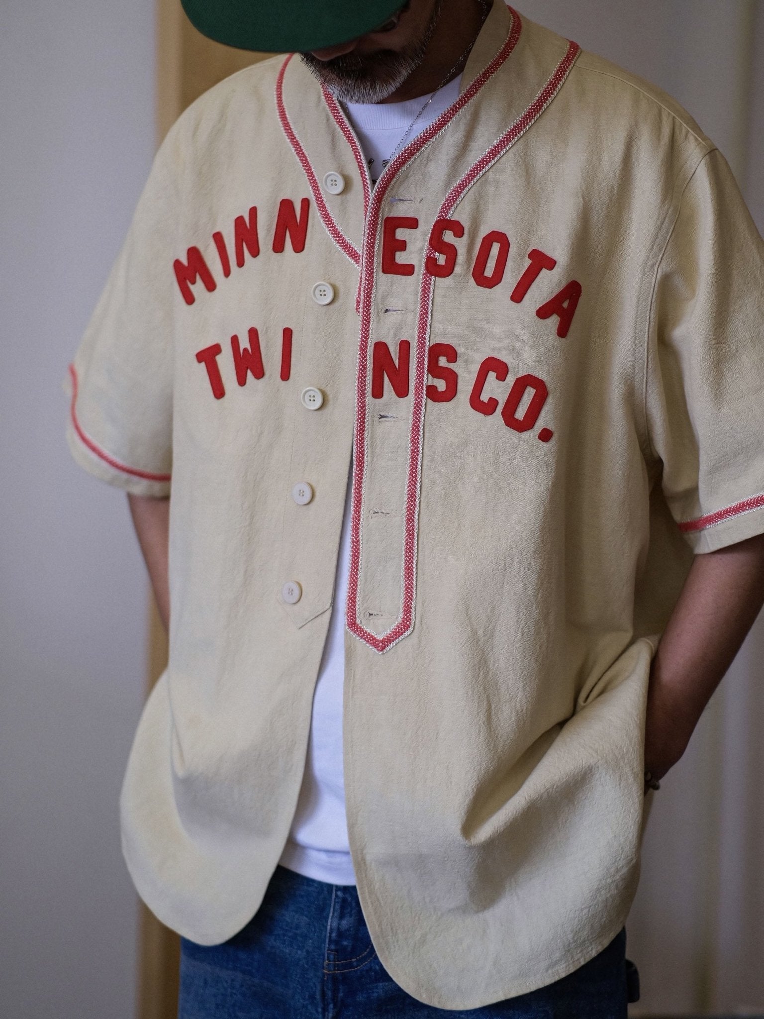 パッチワーク刺繍ロゴと織りテープパイピングが特徴のスタンドカラーベースボールシャツ