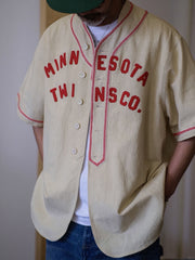 パッチワーク刺繍ロゴと織りテープパイピングが特徴のスタンドカラーベースボールシャツ