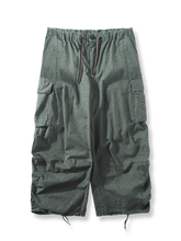 グリッドテクスチャー生地と大型カーゴポケット、シャーリングデザインが特徴のタクティカルアウトドアパラトルーパーパンツの全体像。