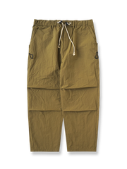 シワ感テクスチャーナイロンのパラシュートパンツ全体正面画像とダブルプリーツ、ポケットディテール。