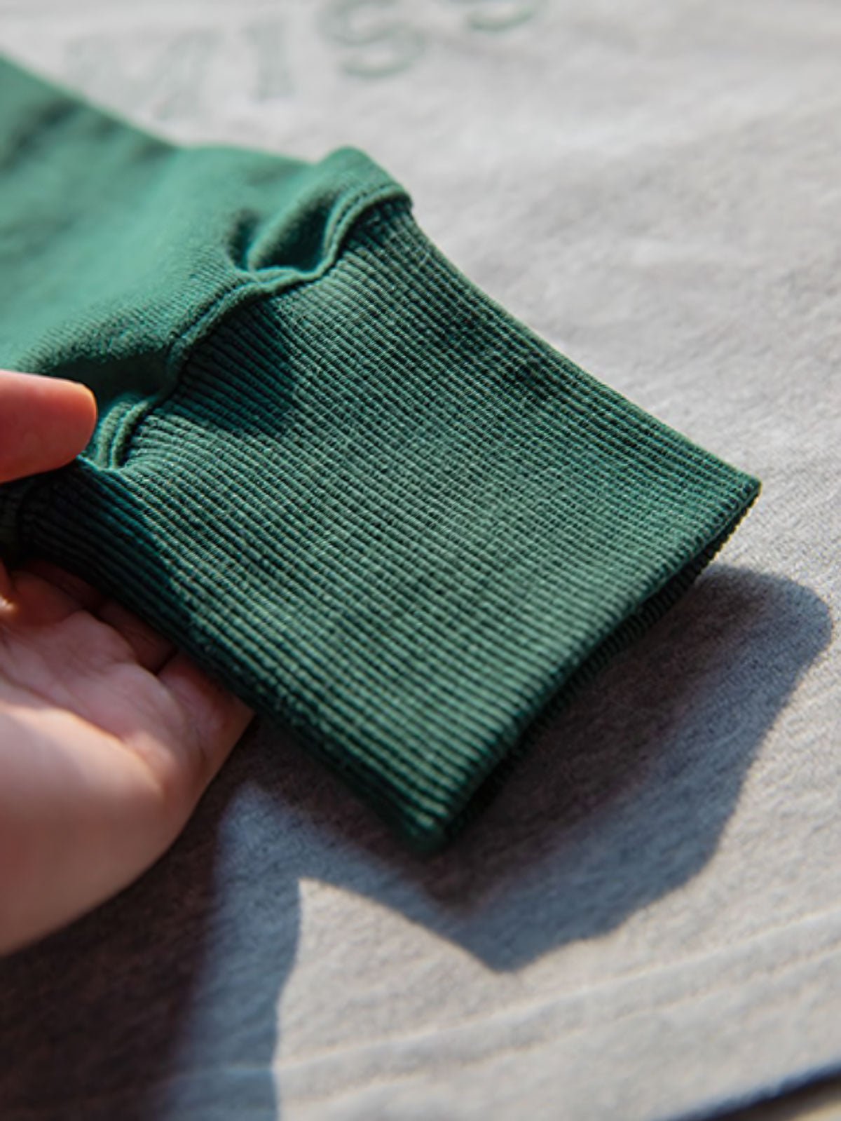 詳細画像:Tシャツのエンブレムプリントと配色袖口のディテール