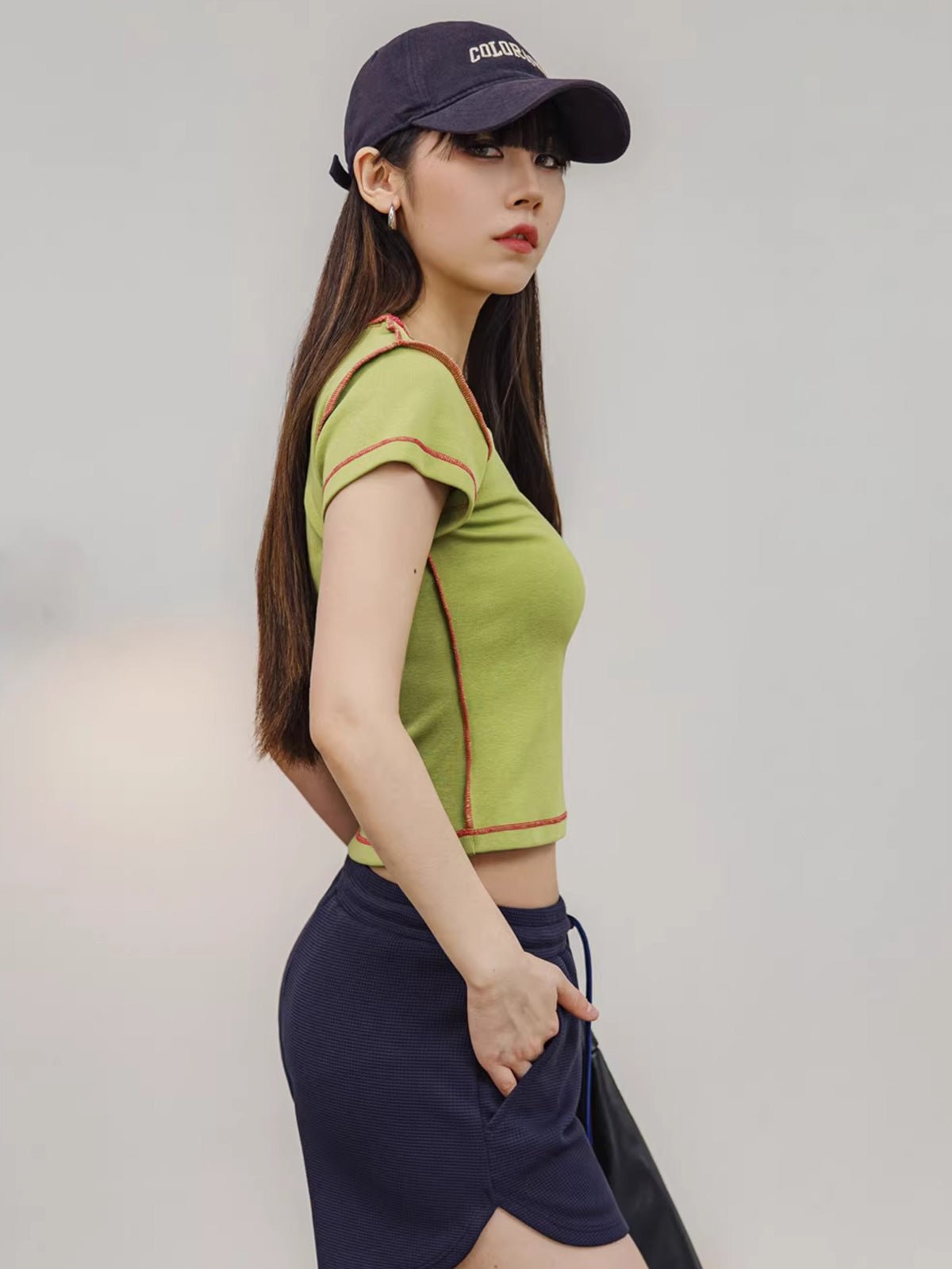 モデルがPESSOA CLUBのアボカドグリーン半袖ニットTシャツを着用し、夏の活動的なスタイルを展示